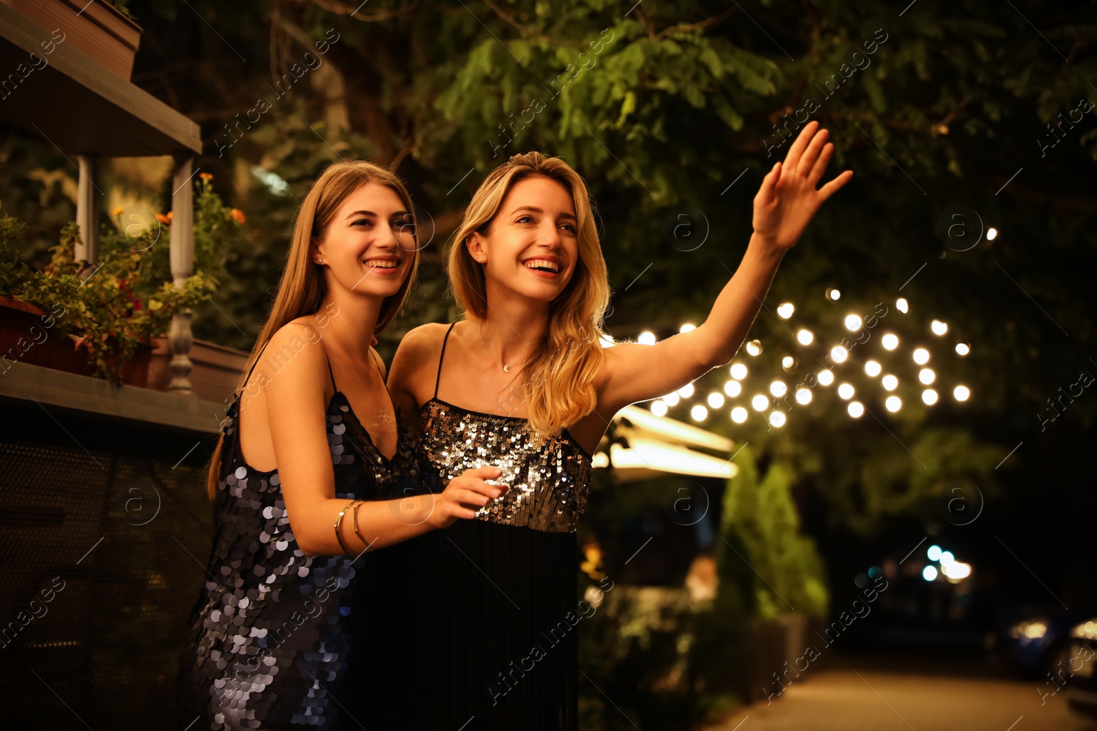 Photo of Young women catching taxi on city street at night