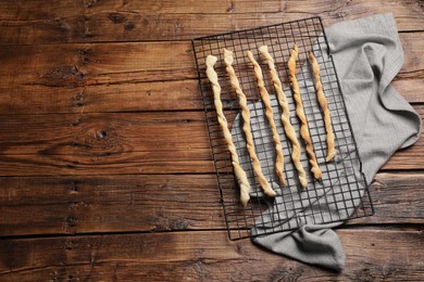 Photo of Rack with homemade breadsticks on wooden table, top view and space for text. Cooking traditional grissini