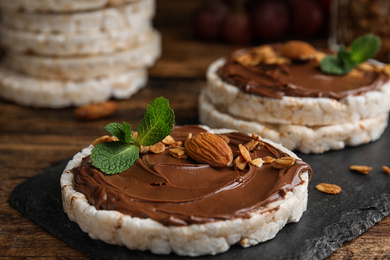 Puffed rice cakes with chocolate spread, nuts and mint on wooden table, closeup