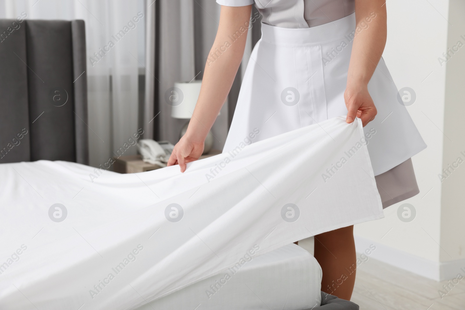 Photo of Maid making bed in hotel room, closeup