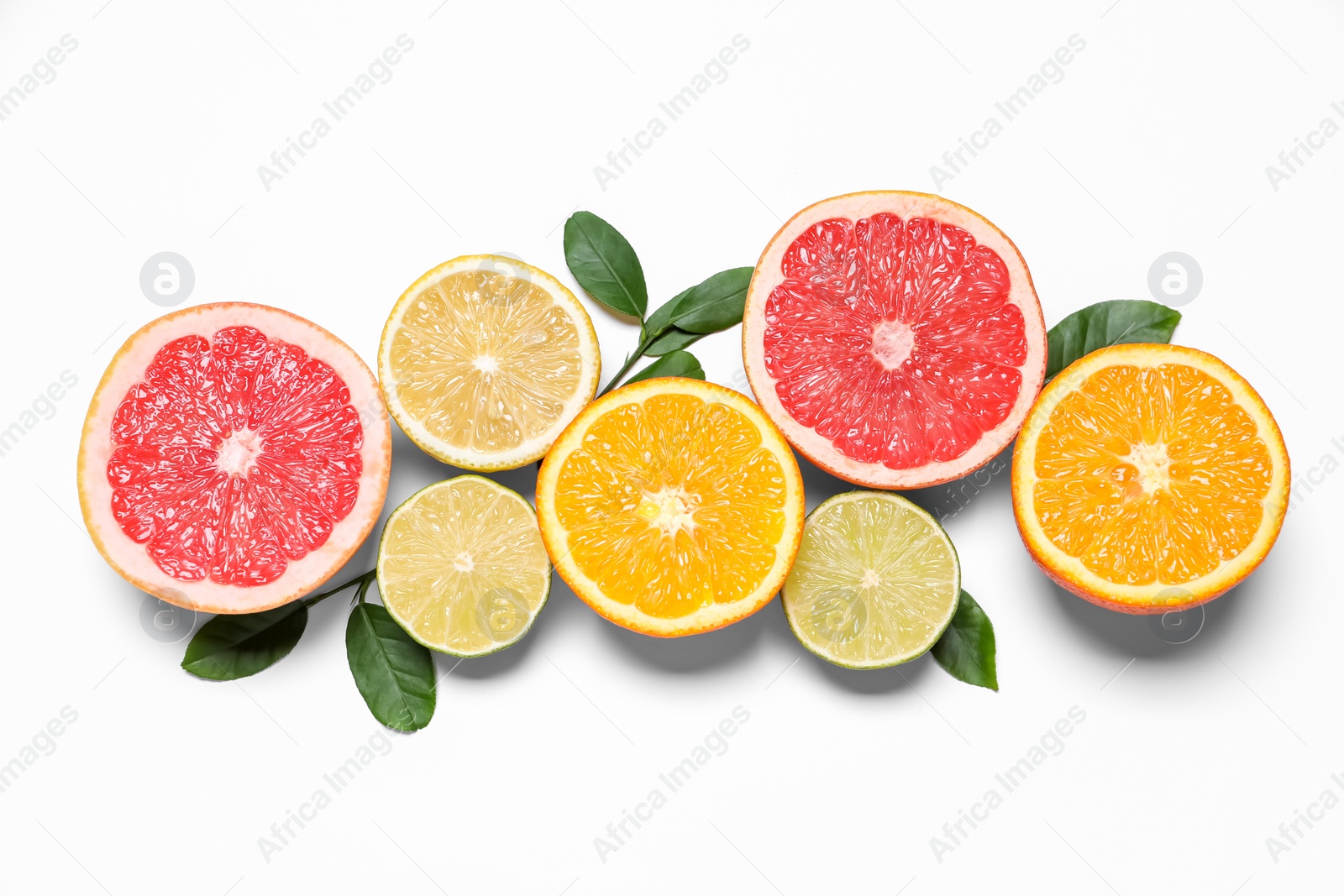 Photo of Different cut citrus fruits and leaves on white table, flat lay