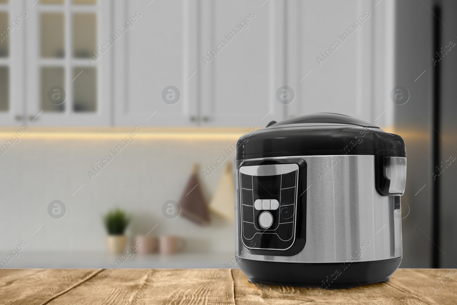 Image of Modern electric multi cooker on wooden table in kitchen. Space for design