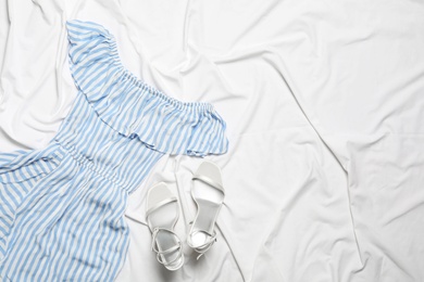 Photo of Stylish light blue dress and shoes on white fabric, flat lay. Space for text