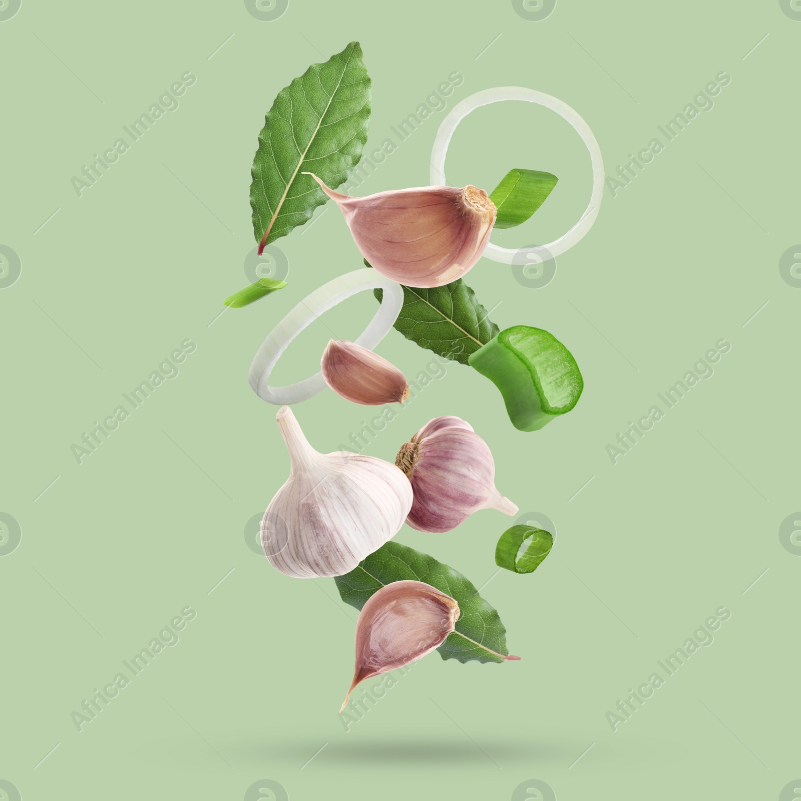 Image of Different spices falling on light green background