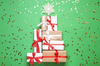 Photo of Christmas tree made with different gift boxes on green background, flat lay