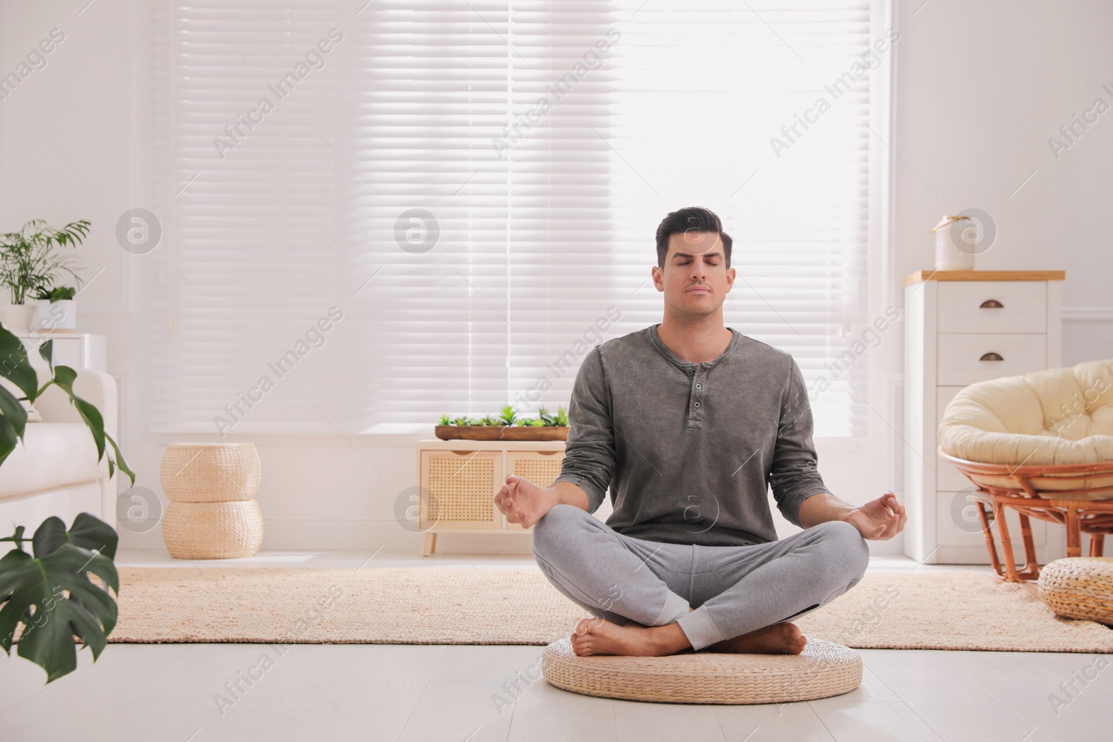 Photo of Man meditating on wicker mat at home. Space for text