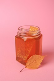 Photo of Jar with honey and autumn leaf on pink background