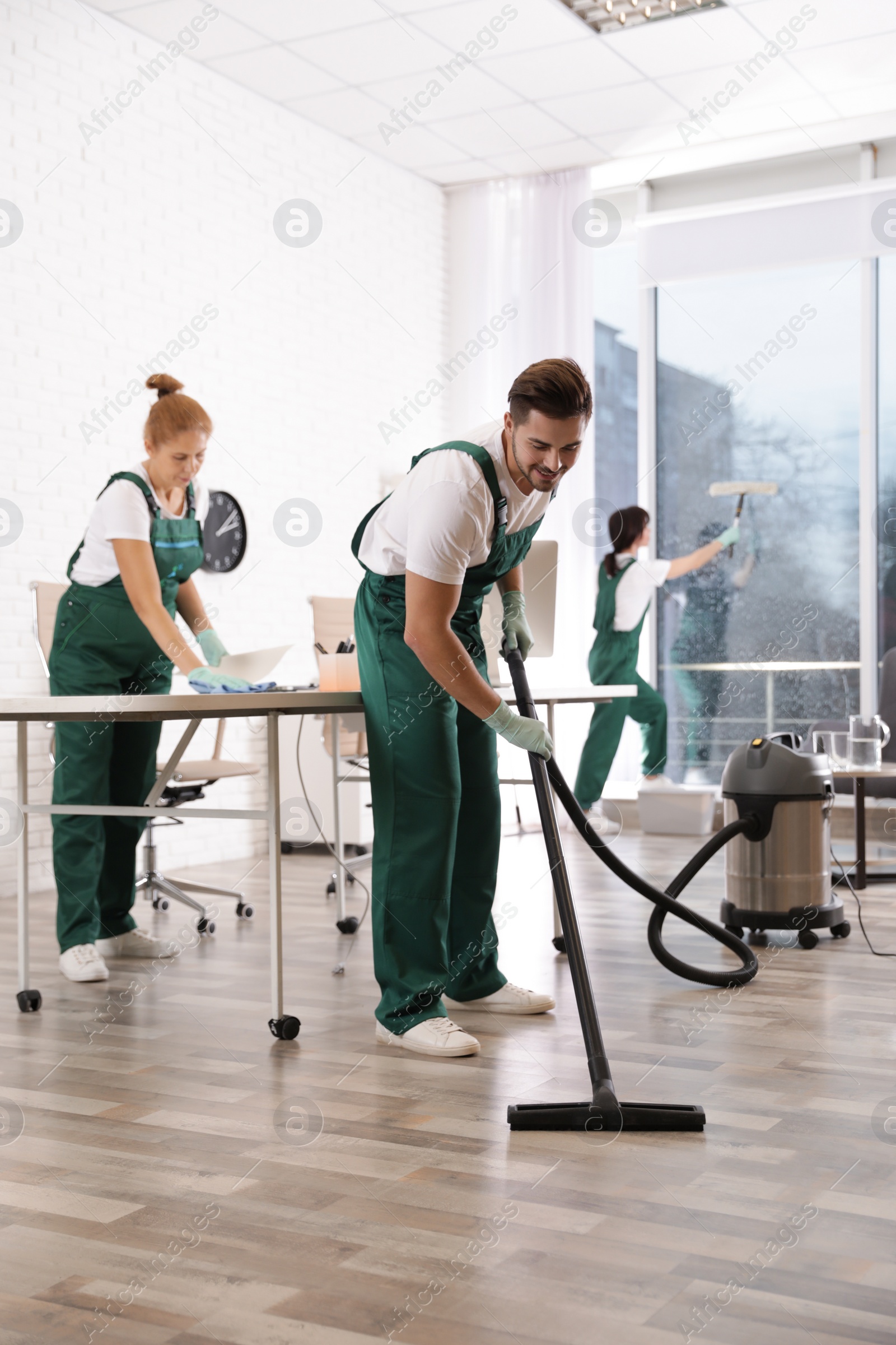 Photo of Team of professional janitors working in modern office. Cleaning service