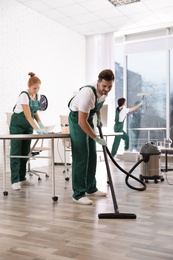 Photo of Teamprofessional janitors working in modern office. Cleaning service