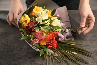 Photo of Woman with beautiful bouquet of freesia flowers on grey background