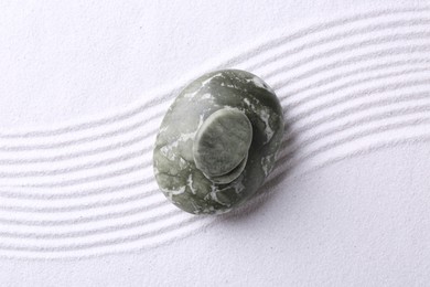 Photo of Zen garden stones on white sand with pattern, top view