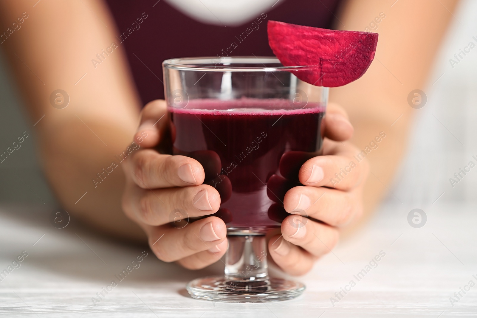 Photo of Woman with glass of beet smoothie at table, closeup