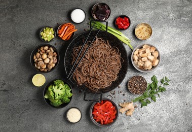 Photo of Wok with noodles, chicken and other products on grey table, flat lay