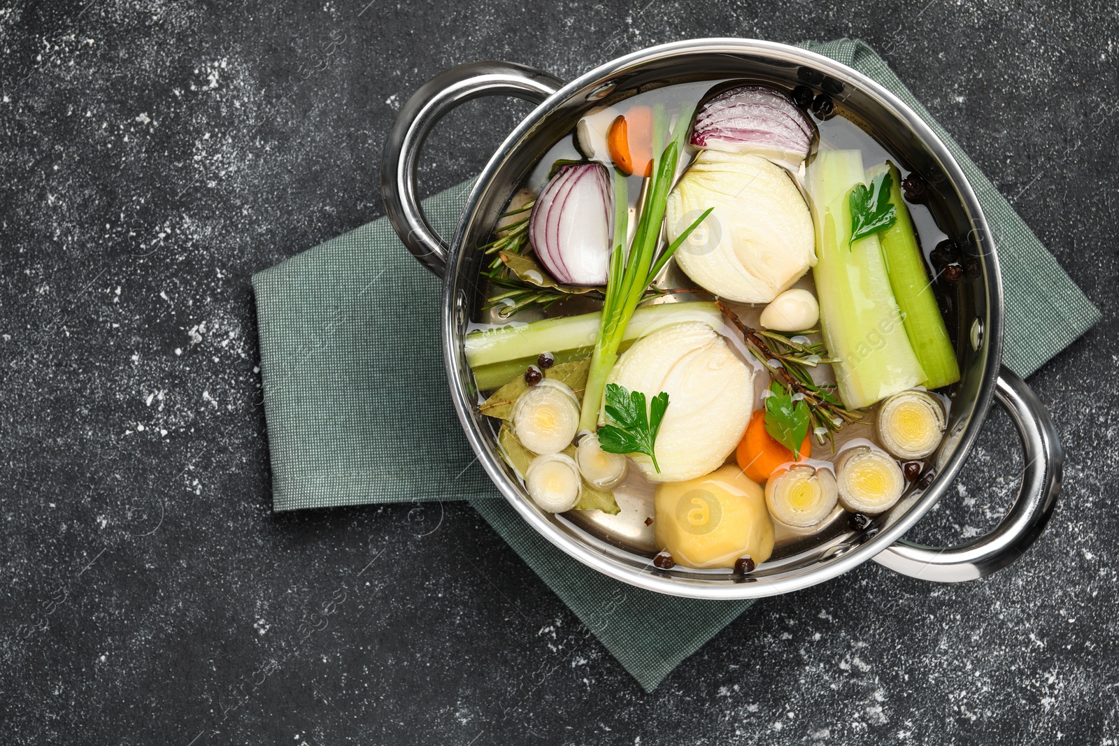 Photo of Different ingredients for cooking tasty bouillon in pot on black table, top view. Space for text