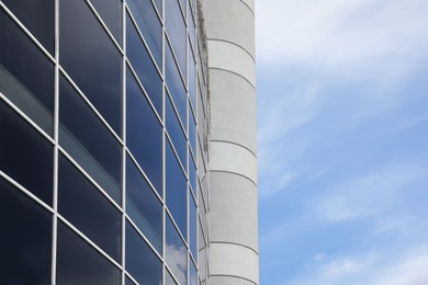 Modern building with tinted windows against sky, low angle view. Urban architecture