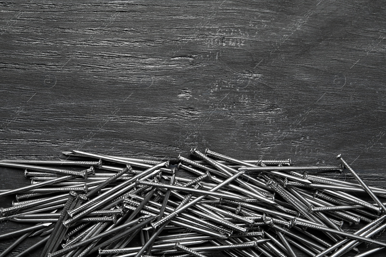 Photo of Pile of metal nails on grey wooden background, flat lay. Space for text