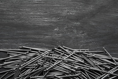 Photo of Pile of metal nails on grey wooden background, flat lay. Space for text