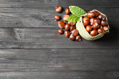 Photo of Fresh sweet edible chestnuts on black wooden table, flat lay. Space for text