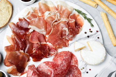 Photo of Tasty prosciutto served on light grey marble table, flat lay