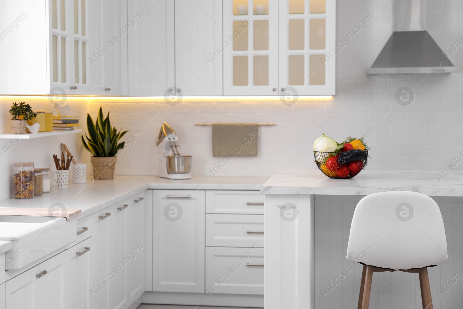 Photo of Modern kitchen interior with different vegetables on white table