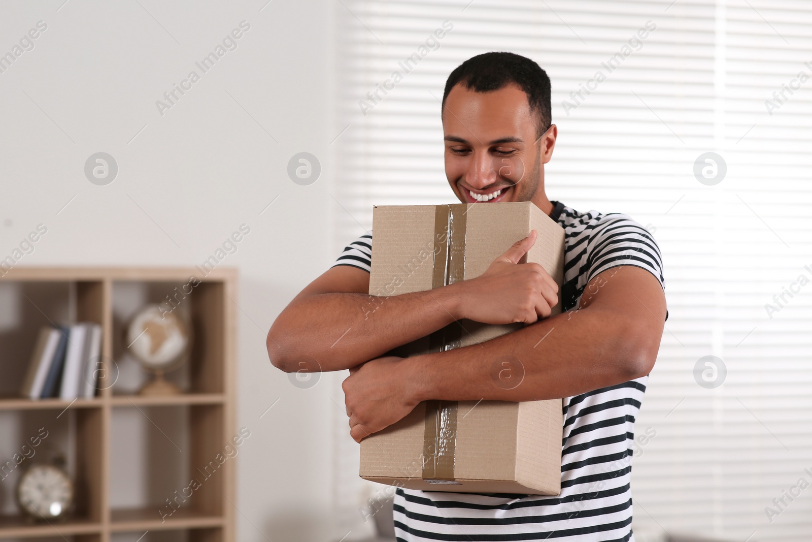 Photo of Happy young man with parcel at home. Internet shopping