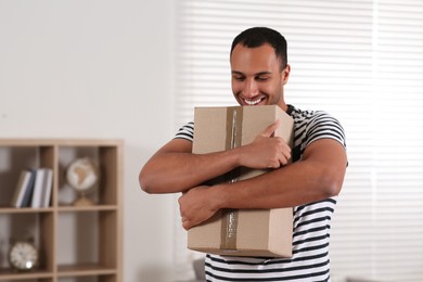 Photo of Happy young man with parcel at home. Internet shopping