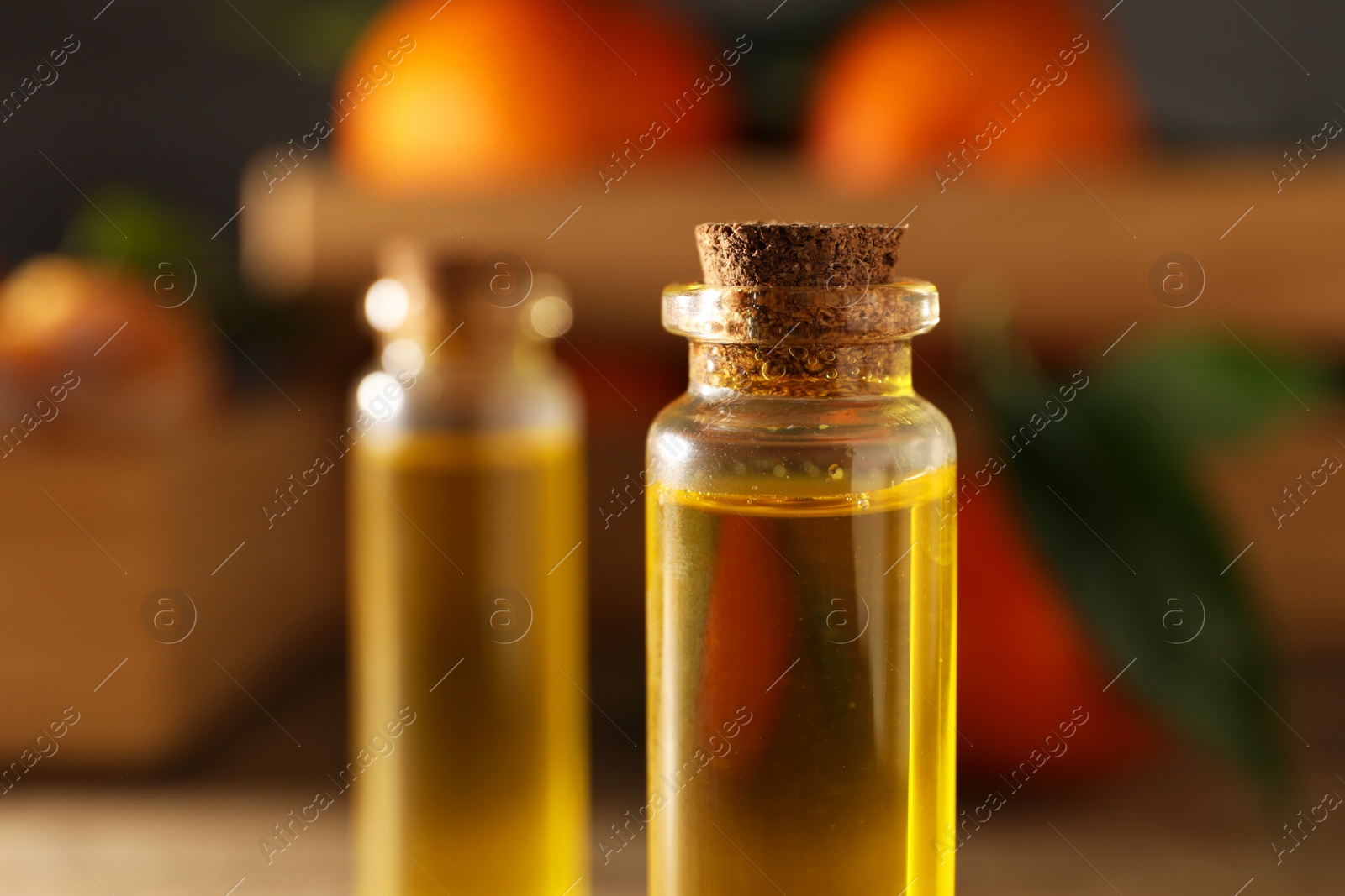 Photo of Bottles of tangerine essential oil on table, closeup