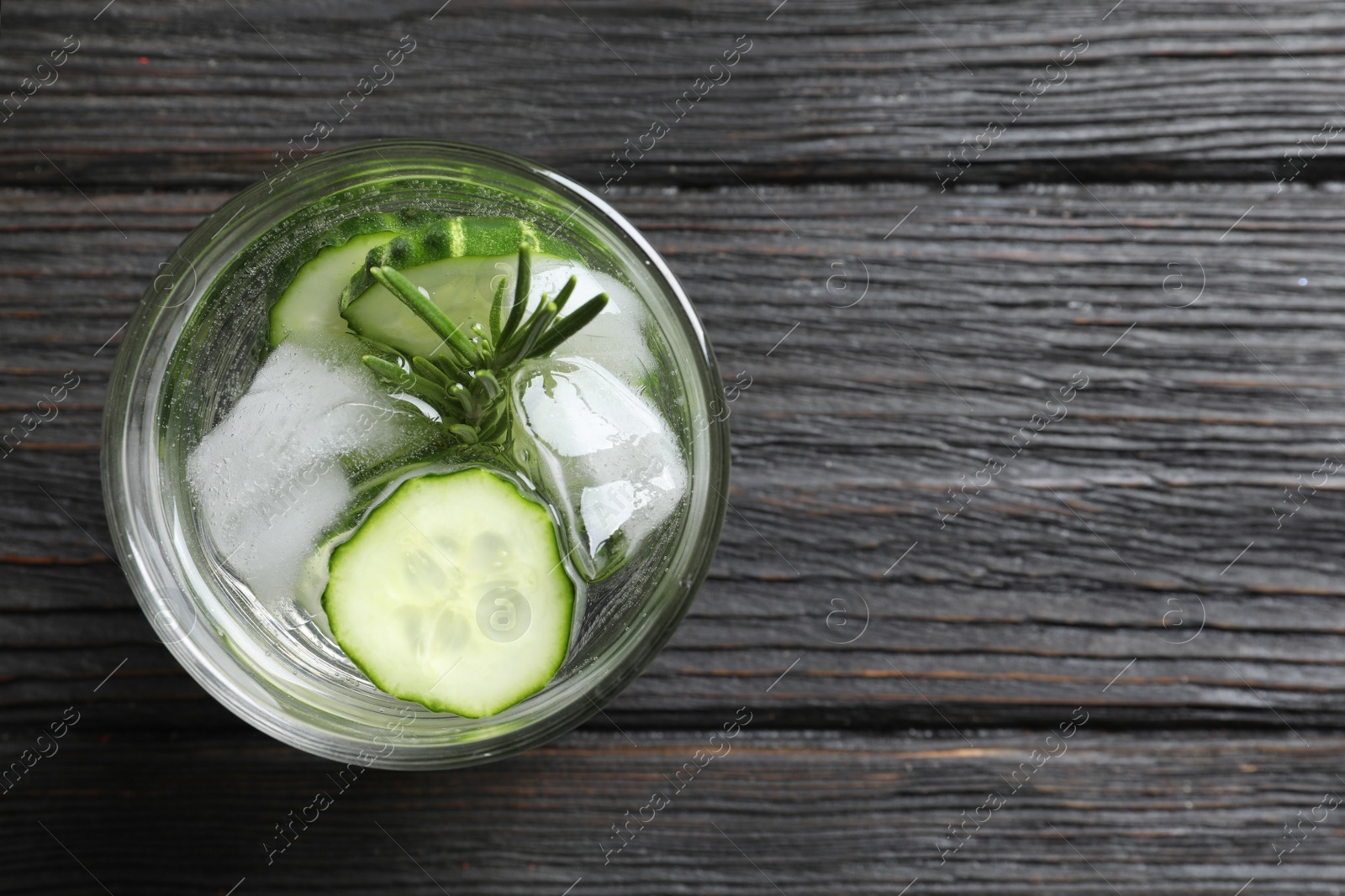 Photo of Glass of fresh cucumber water on wooden table, top view. Space for text