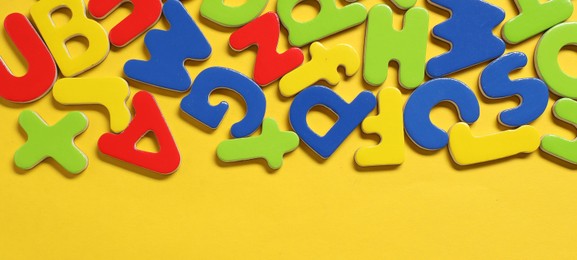 Photo of Learning alphabet. Magnetic letters on yellow background, flat lay. Space for text