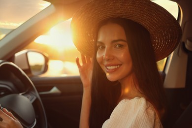 Beautiful young woman sitting in her car. Enjoying trip