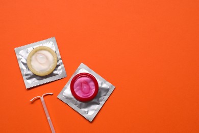 Photo of Contraception choice. Condoms and intrauterine device on terracotta background, flat lay. Space for text