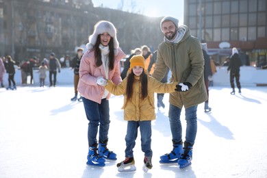 Image of Happy family spending time together at outdoor ice skating rink