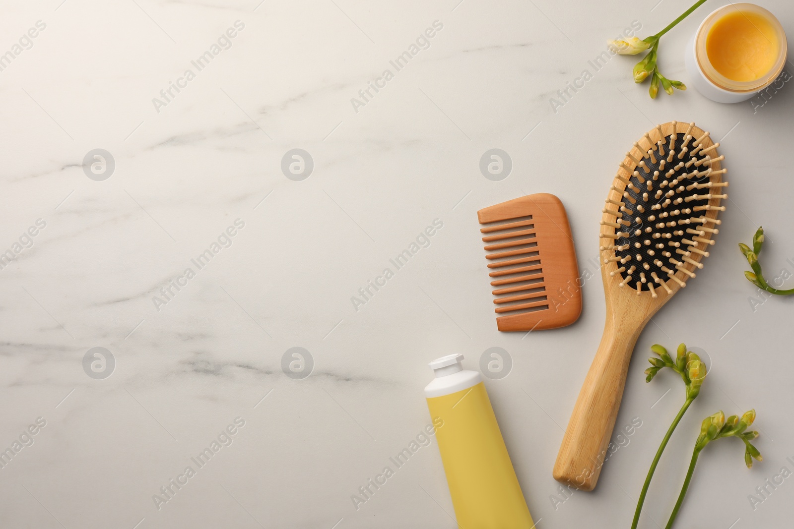 Photo of Flat lay composition with wooden hair brush and comb on white marble table, space for text