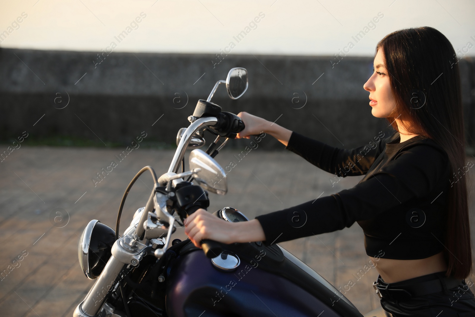 Photo of Beautiful young woman riding motorcycle at sunset