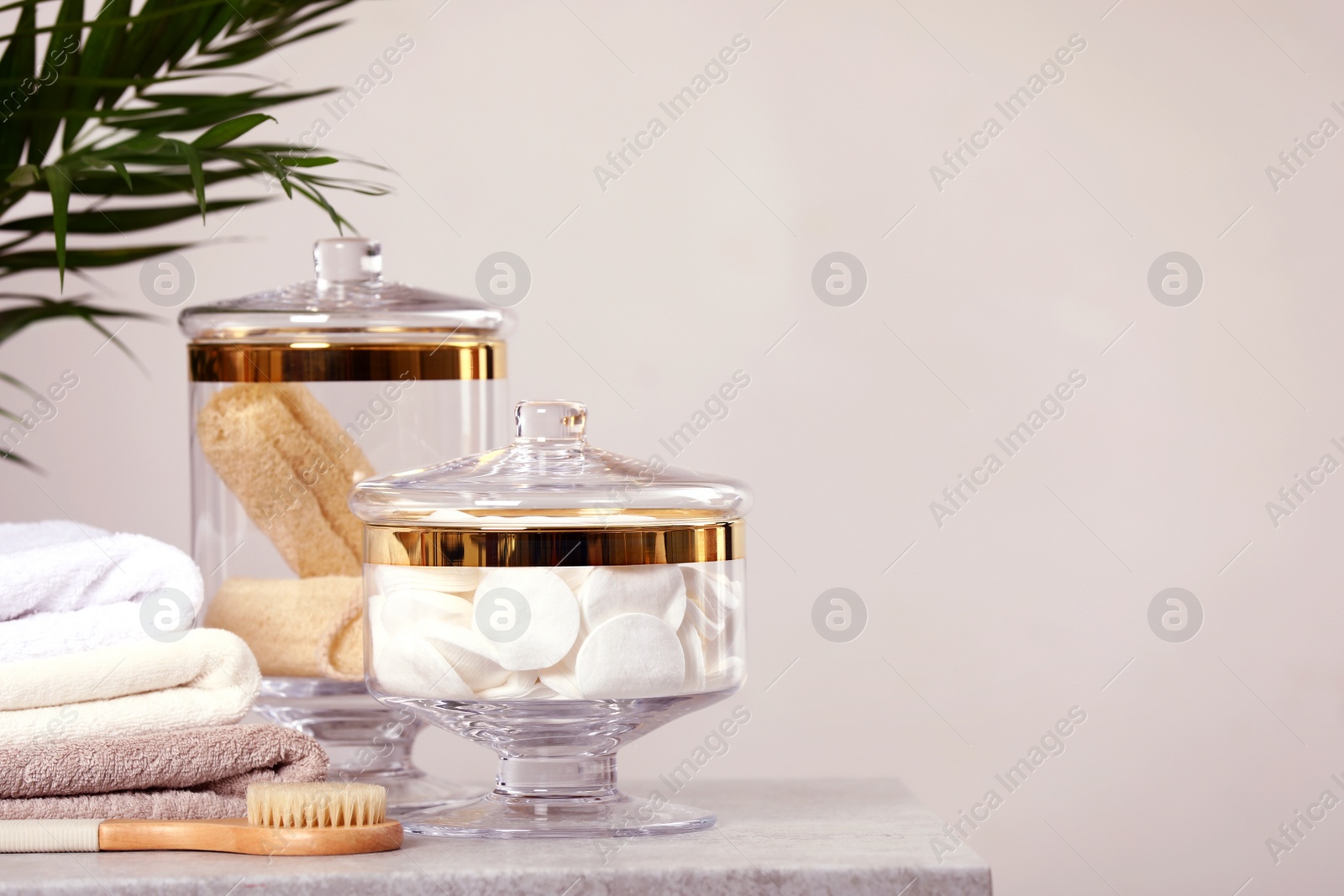 Photo of Composition of glass jar with cotton pads on table near light wall. Space for text