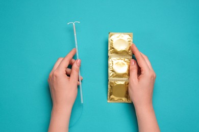 Photo of Woman with condoms and intrauterine device on light blue background, top view. Choosing birth control method