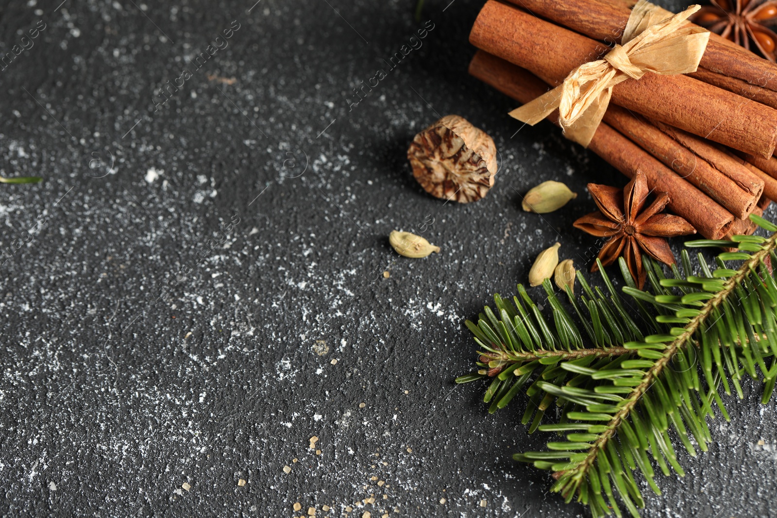 Photo of Different aromatic spices and fir branches on grey textured table, flat lay. Space for text