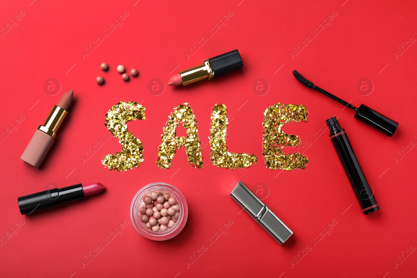 Photo of Word Sale made of golden metallic confetti surrounded by makeup products on red background, flat lay. Black Friday