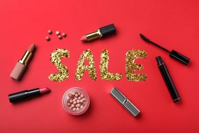 Photo of Word Sale made of golden metallic confetti surrounded by makeup products on red background, flat lay. Black Friday