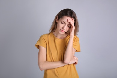 Portrait of stressed young woman on grey background