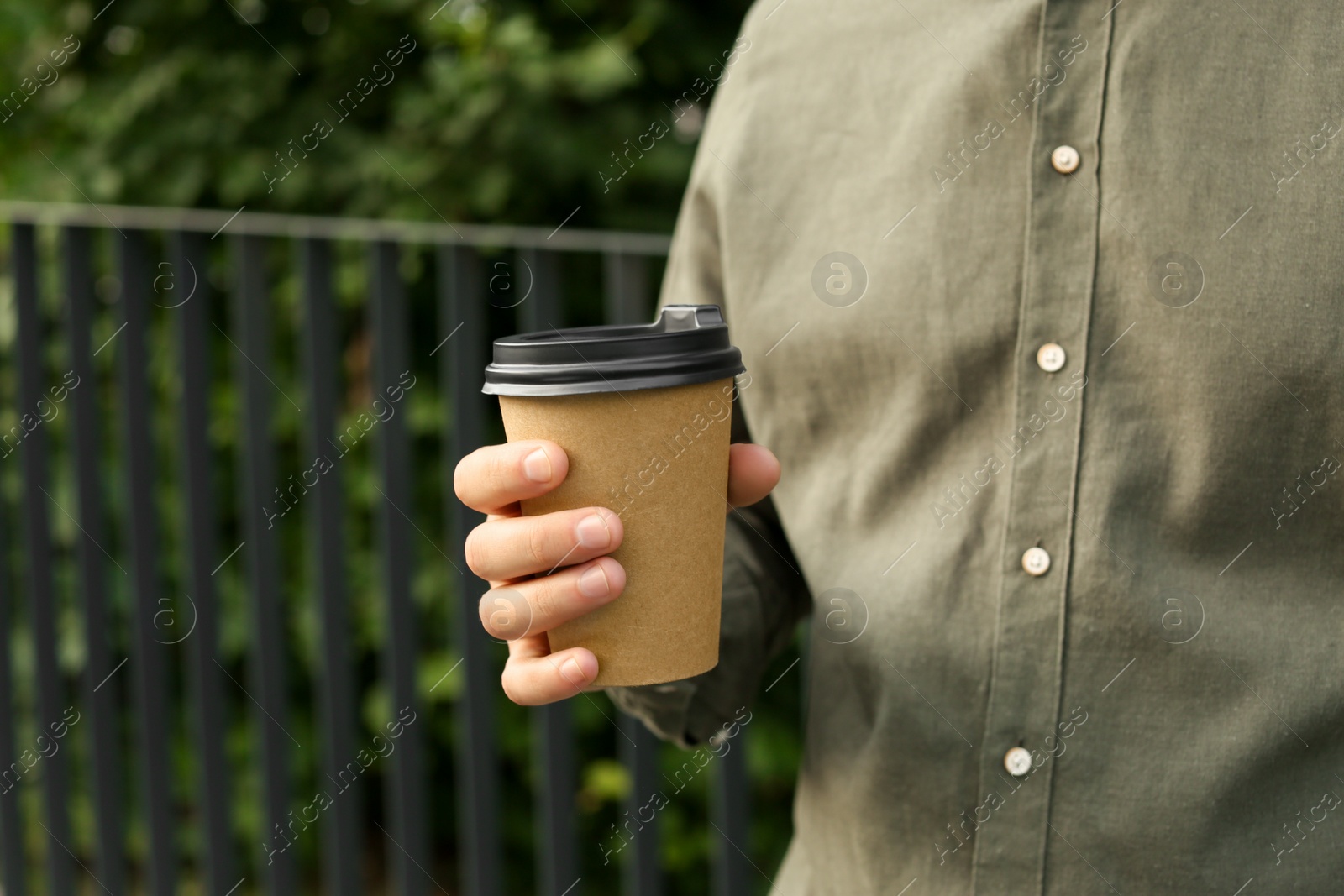 Photo of Coffee to go. Man with paper cup of drink outdoors, closeup. Space for text