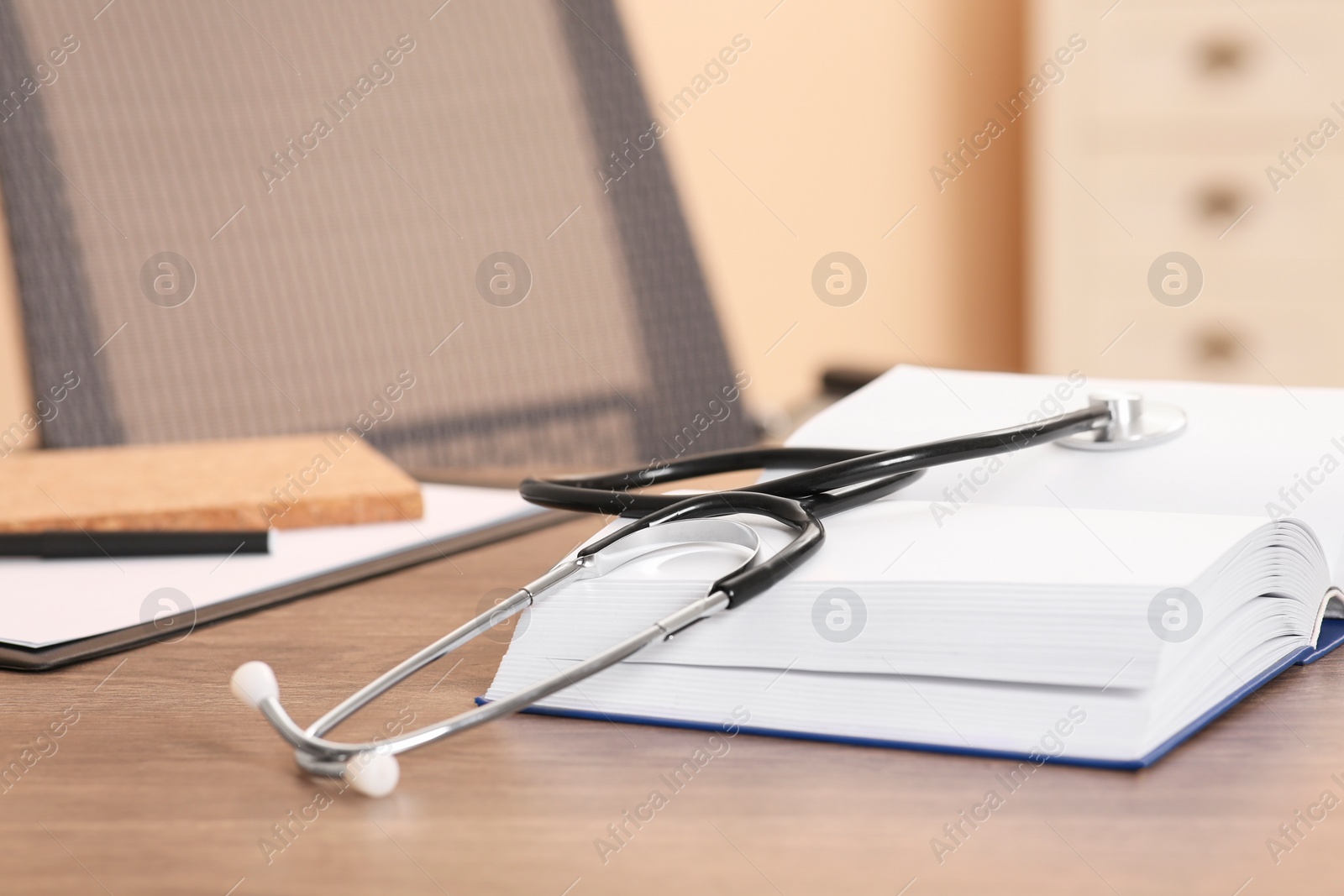 Photo of Book and stethoscope on wooden table indoors, space for text. Doctor education