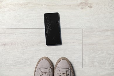 Woman near dropped smartphone on floor, top view. Device repairing