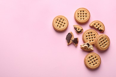 Tasty sandwich cookies with cream on pink background, flat lay. Space for text