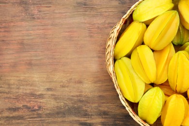 Photo of Delicious ripe carambolas on wooden table, top view. Space for text