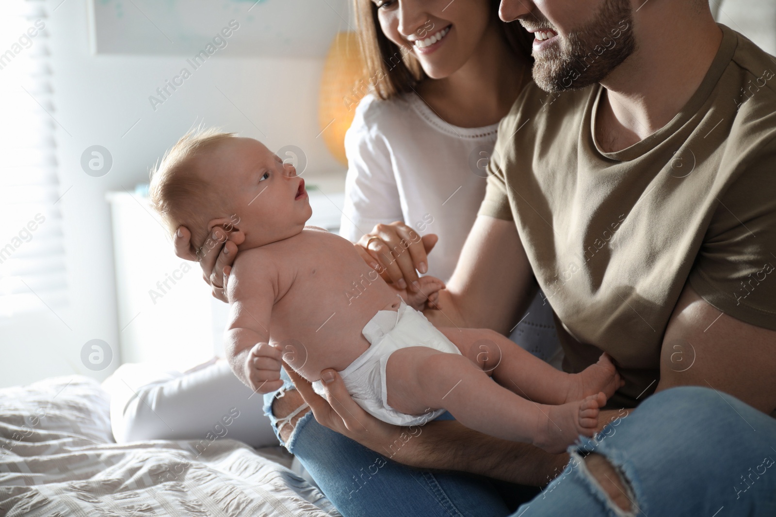 Photo of Happy couple with their newborn baby at home, closeup