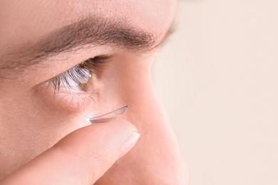 Young man putting contact lens in his eye, closeup