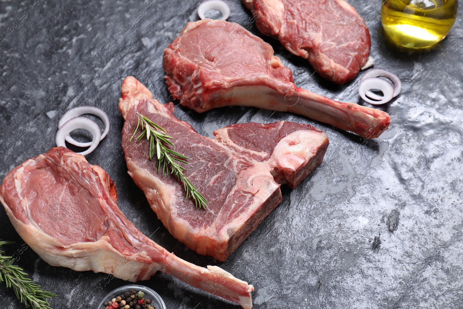 Photo of Fresh raw beef cuts and different spices on grey textured table