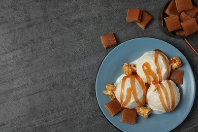 Delicious ice cream with caramel topping on grey table, flat lay. Space for text