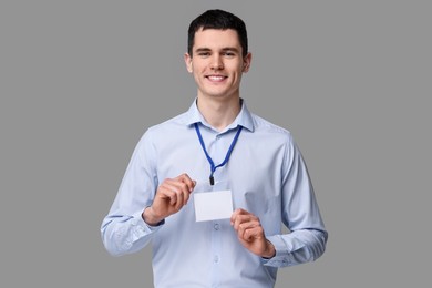 Photo of Smiling man showing empty badge on grey background